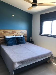 una camera da letto con un letto con pareti blu e un ventilatore a soffitto di OCEAN SUNSET a Saint-Leu