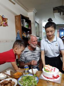un hombre y dos niños parados frente a una mesa con un pastel en Hong Vinh Hotel, en Ho Chi Minh