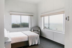 una camera con un letto e una sedia e due finestre di Pacific Hotel Yamba a Yamba