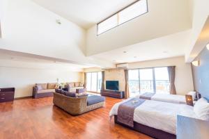 a large bedroom with two beds and a television at Condominium Hotel Monpa in Chatan