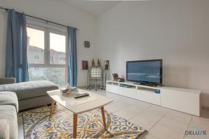 a living room with a couch and a tv at Restful 1BR at Mediterranean Discovery Gardens by Deluxe Holiday Homes in Dubai