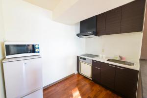 uma cozinha com um frigorífico branco e um lavatório em Condominium Hotel Monpa em Chatan