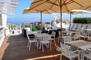 un balcone con tavoli, sedie e ombrellone di Hotel Plaza a Sorrento