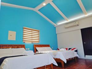 a room with three beds and a blue wall at Water 168 Homestay in Xiaoliuqiu