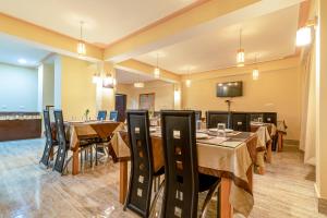 a dining room with tables and chairs and a flat screen tv at Magellan's The Golden Bridge in Lachung