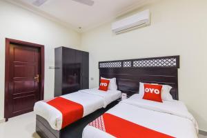 two beds in a room with red and white pillows at Ras Al Hadd Waves Hotel in Al Ḩadd