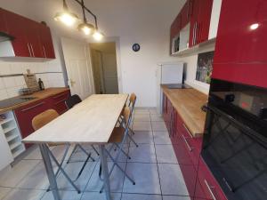 cocina con mesa de madera y armarios rojos en Colmar Suites - Résidence en Colmar