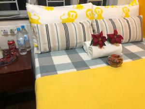 1 cama con almohadas amarillas y blancas y flores rojas en Delta Lounge, en Hong Kong