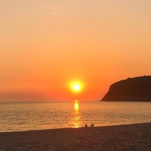 una puesta de sol en la playa con gente en la playa en Kavkaz Hotel, en Olginka