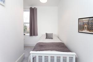 a bedroom with a white bed in a white room at Clarendon in Leicester