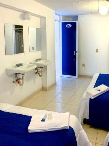 uma casa de banho com 2 camas, um lavatório e uma porta azul em La Casa del Expositor em Guadalajara