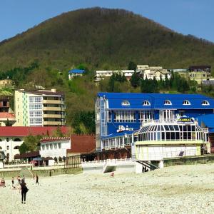 オリギンカにあるKavkaz Hotelの山の隣の浜辺の青い建物