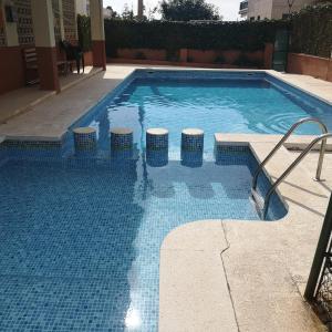 een zwembad met vier krukken erin bij Apartamentos Lorena 1A in Segur de Calafell