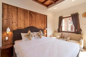 a bedroom with a large bed and two chairs at Little Colmar - Homestay & Pottery Studio in Ha Long