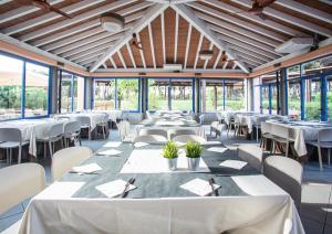 una sala da pranzo con tavoli, sedie e finestre di Garden Toscana Resort a San Vincenzo