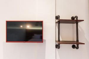 a television hanging on a wall with two shelves at RedDoorz Plus At Mitrotel Medan in Sunggal +20 photos