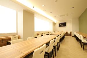 an empty lecture room with wooden tables and chairs at AB Hotel Yukuhashi in Yukuhashi