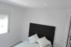 a bedroom with a bed with a black headboard and two pillows at A10minutosdelaplayaandando in Málaga