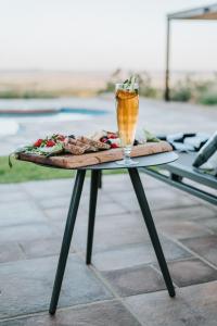 a table with a drink and a plate of food at The Feather Hill Boutique Hotel in Potchefstroom