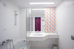 a white bathroom with a sink and a shower at Skiathos Palace Hotel in Koukounaries