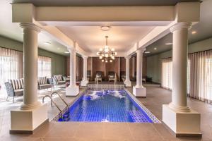 a pool in a hotel lobby with columns and a chandelier at The Feather Hill Boutique Hotel in Potchefstroom