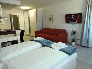 ein Wohnzimmer mit einem Bett und einem roten Sofa in der Unterkunft 203 Rom, Studio Apartment, 38m2 1-4 Pers in Klagenfurt am Wörthersee