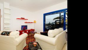 a living room with two white chairs and a television at Apartment La Marina Sea Views with terrace By PVL in Arrecife