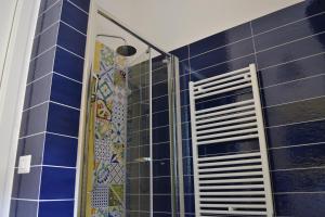 y baño con ducha de azulejos azules. en GARDENIA, en Salerno