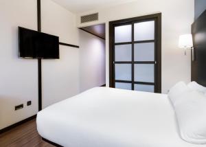 um quarto com uma cama branca e uma televisão de ecrã plano em B&B HOTEL Madrid Getafe em Getafe