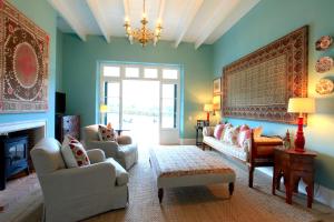 a living room with blue walls and a chandelier at La Cotte The Manor House in Franschhoek
