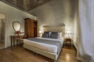 a bedroom with a large bed and a mirror at Hotel Bretagna Heritage - Alfieri Collezione in Florence