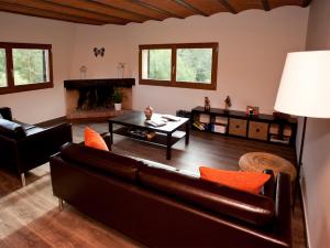 a living room with a leather couch and a fireplace at Mas Pinoses in Les Llosses