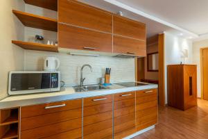 a kitchen with wooden cabinets and a sink and a microwave at Glow Apartments, Apartament Meriwa Sopot in Sopot