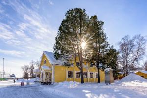 una casa amarilla con un árbol en la nieve en Putiikkihotelli Kemi 1932, en Kemi