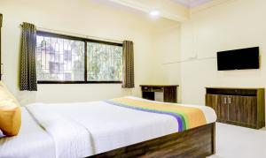a bedroom with a bed and a flat screen tv at Hotel Bestow Inn Koregaon Park Pune -Near Osho Ashram in Pune