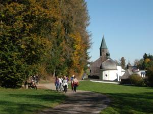 a group of people walking down a path near a church at Gasthof Alte Post in Bischofsmais
