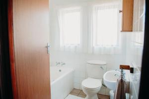 a bathroom with a toilet and a tub and a sink at Port Edward Holiday Resort in Port Edward