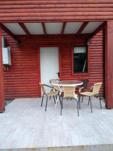 a patio with a table and chairs in front of a red wall at Cabaña de Lore in Licán Ray