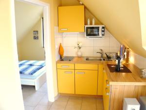 a small kitchen with yellow cabinets and a sink at Apartments Sonnendeck in Warnemünde