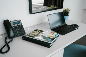 a desk with a phone and a laptop and a book at Hotel Blue in Zagreb
