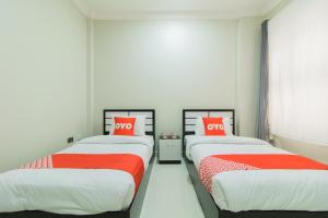 two beds in a room with red and white sheets at OYO 106 Muscat Grand Hotel Apartment in Seeb