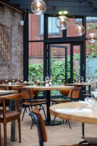a restaurant with tables and chairs and windows at Chasse Hotel in Amsterdam