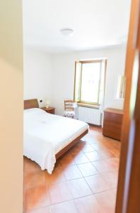 a bedroom with a white bed and a tiled floor at Welcome Traveller IL BORGO APARTMENT in Bardolino