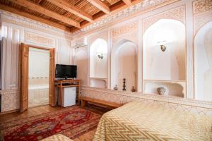 a hotel room with a bed and a tv at Boutique Hotel Minzifa in Bukhara