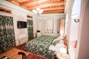 Un dormitorio con una cama y un televisor. en Boutique Hotel Minzifa, en Bukhara