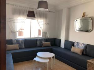 a living room with a blue couch and a table at Jolie appartement vue mer in M'diq