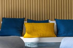 a bed with blue and yellow pillows on it at Calarossa Bay Resort in Porto-Vecchio