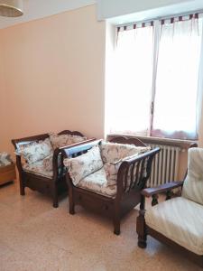 two chairs and a couch in a room with a window at Appartamento Beatrice in Pistoia