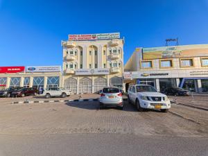 Super OYO 108 Marsa Al Masafar Hotel Apartment في صور: سيارتين متوقفتين في موقف للسيارات امام مبنى