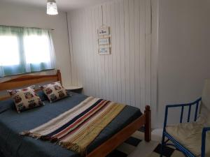 1 dormitorio con cama, ventana y silla en La Casita de Monte en Monte Hermoso